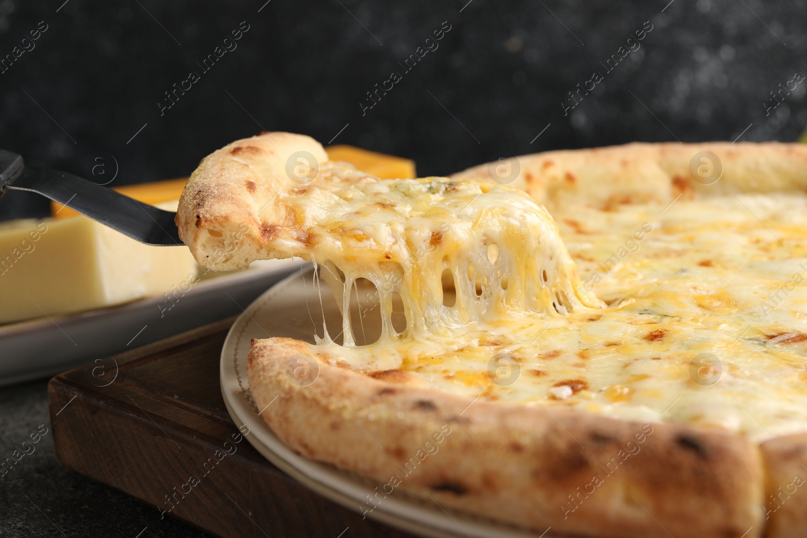 Photo of Taking piece of delicious cheese pizza at table, closeup