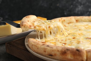 Photo of Taking piece of delicious cheese pizza at table, closeup