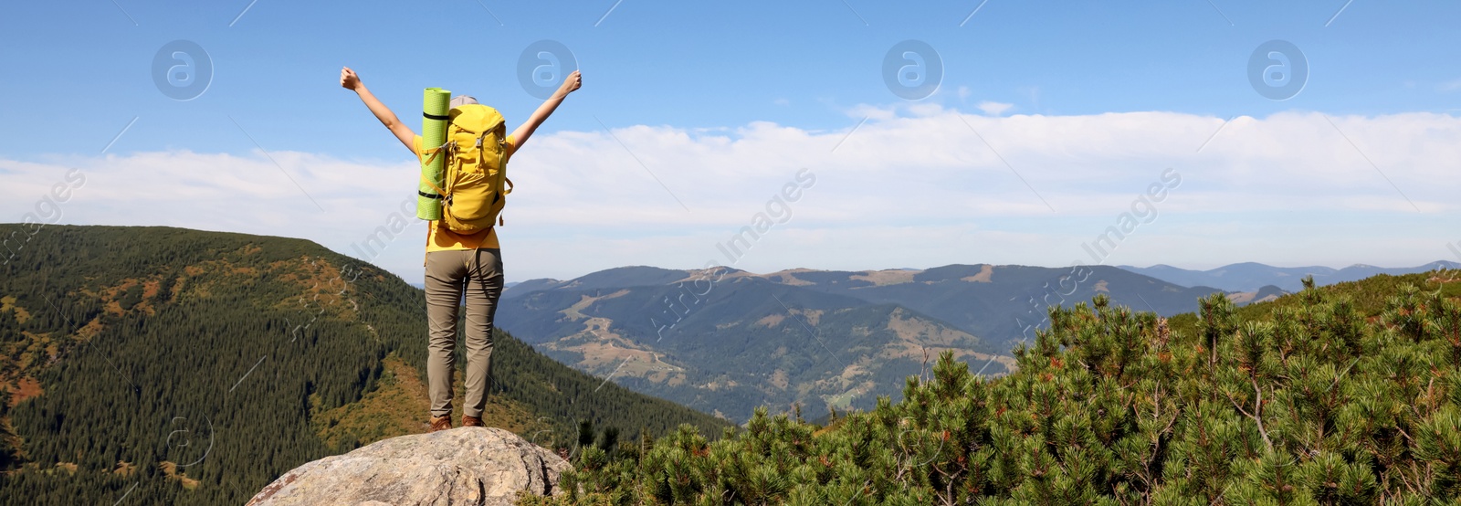 Image of Young woman with backpack on peak in mountains, back view. Banner design