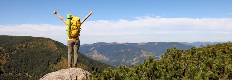 Image of Young woman with backpack on peak in mountains, back view. Banner design