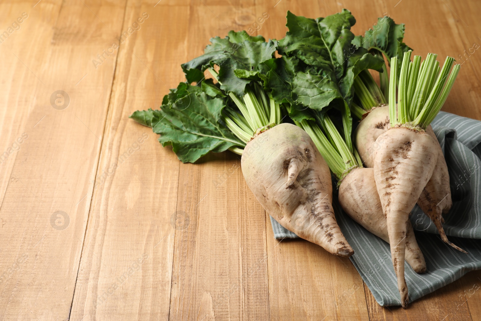 Photo of Fresh sugar beets with leaves on wooden table. Space for text