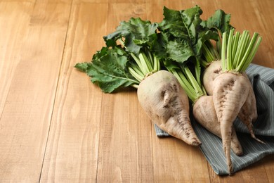 Photo of Fresh sugar beets with leaves on wooden table. Space for text