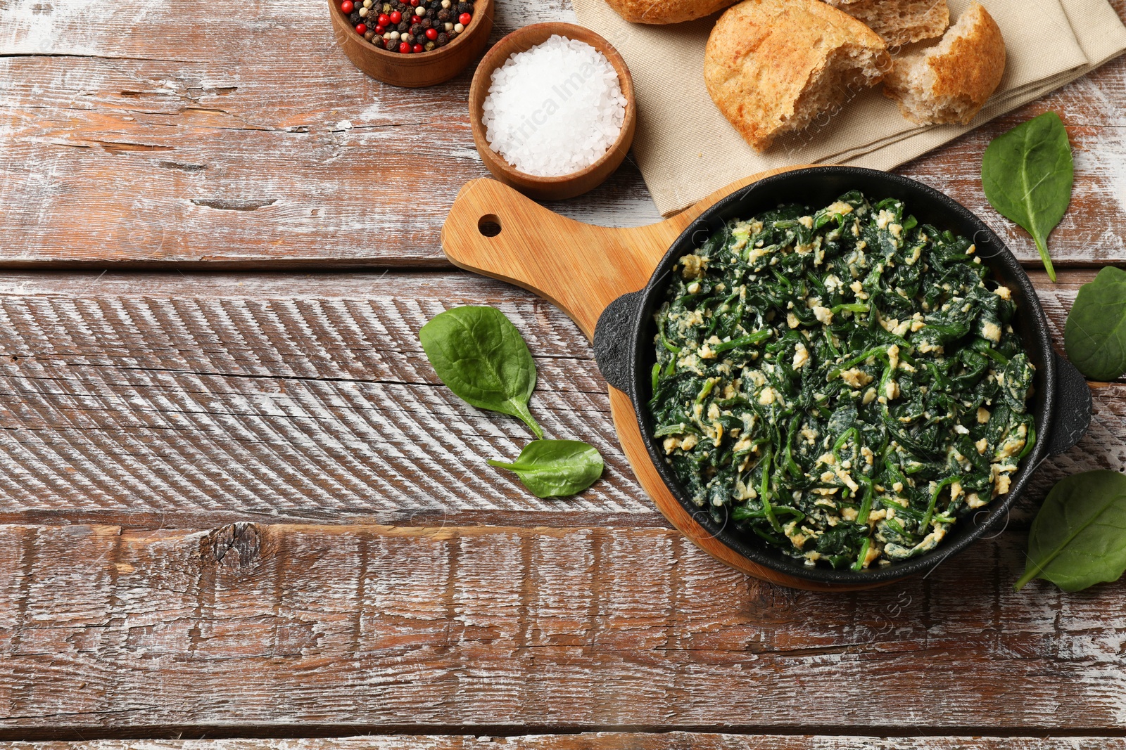 Photo of Tasty spinach dip with eggs in dish served on wooden table, flat lay. Space for text