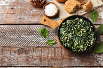 Photo of Tasty spinach dip with eggs in dish served on wooden table, flat lay. Space for text