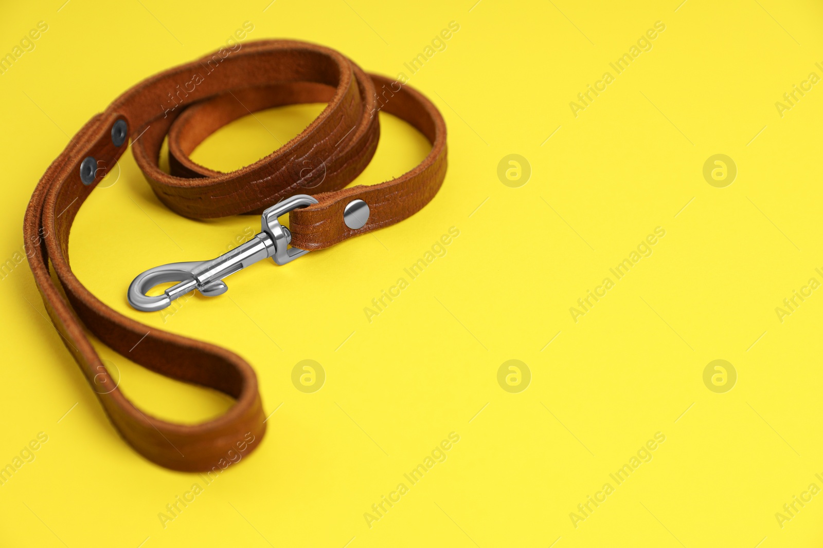 Photo of Brown leather dog leash on yellow background. Space for text