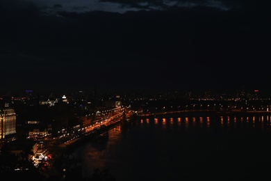 Photo of KYIV, UKRAINE - MAY 21, 2019: Beautiful view of night cityscape with illuminated buildings near river