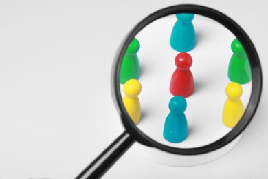 Photo of Magnifying glass over colorful pawns on white background, space for text. Recruiter searching employee