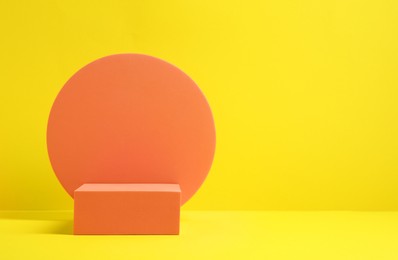 Photo of Different orange geometric figures on yellow background, space for text. Stylish presentation for product