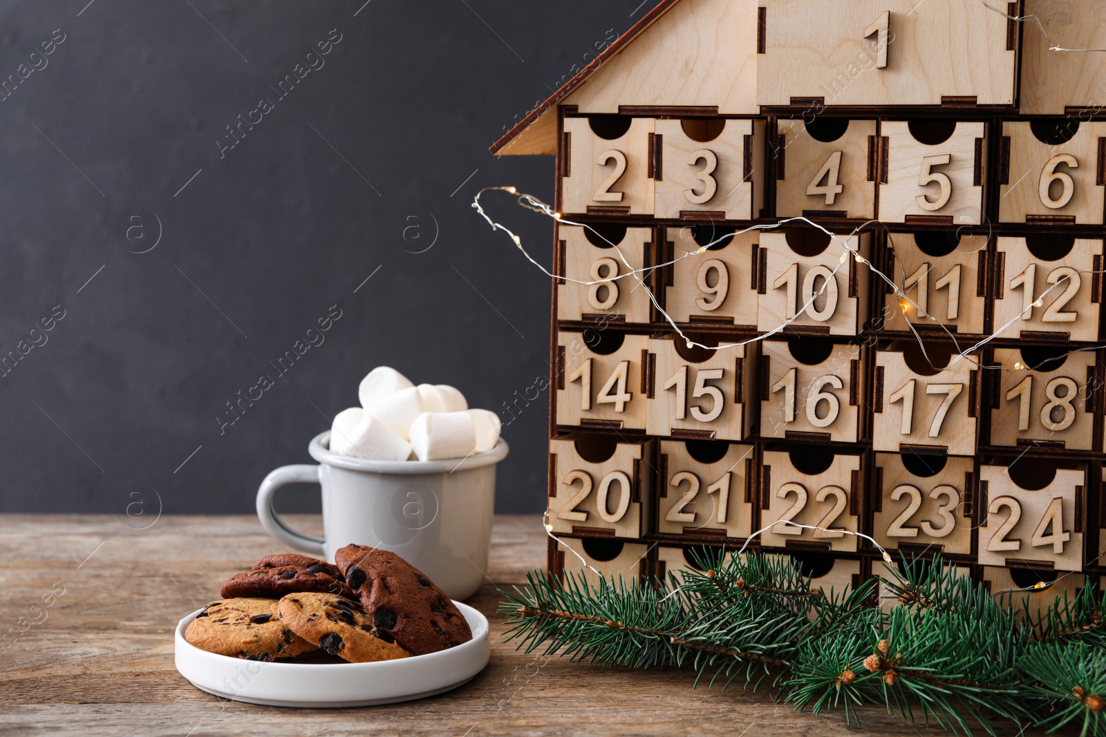 Photo of House shaped Christmas advent calendar, cookies and hot cocoa drink on wooden table