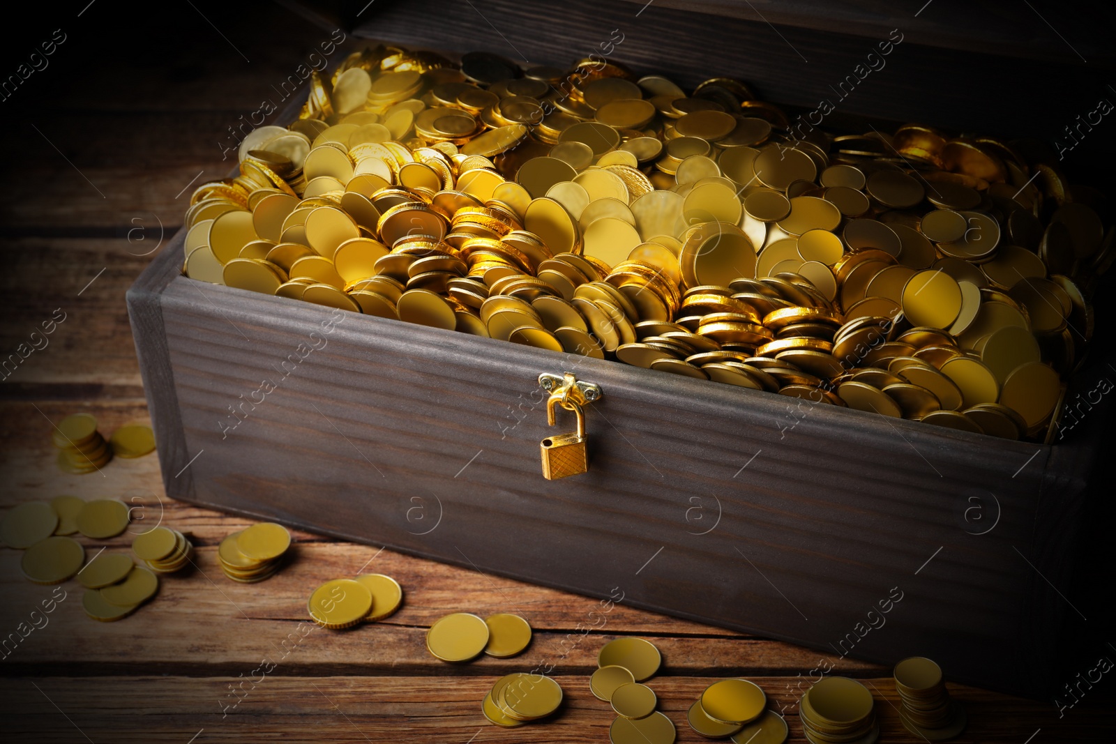 Image of Open treasure chest with gold coins on wooden table