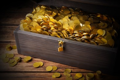 Open treasure chest with gold coins on wooden table