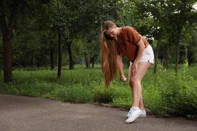 Photo of Woman applying insect repellent onto leg in park. Tick bites prevention