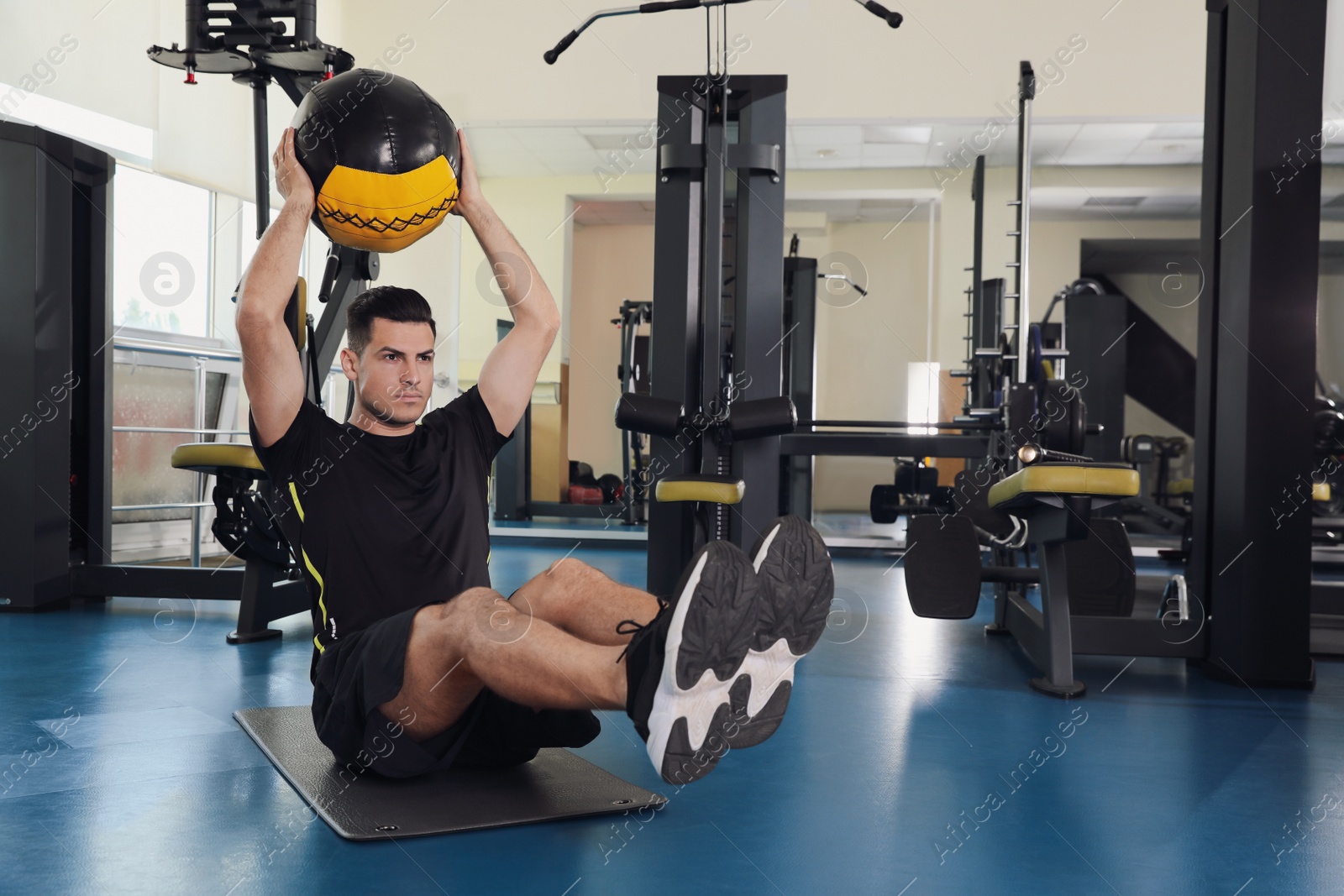 Photo of Athletic man exercising with medicine ball in modern gym. Space for text