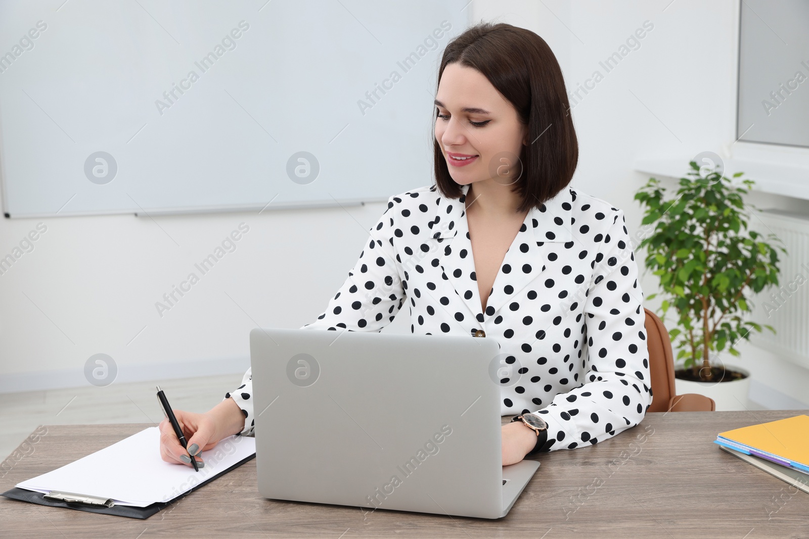 Photo of Happy young intern working at table in modern office