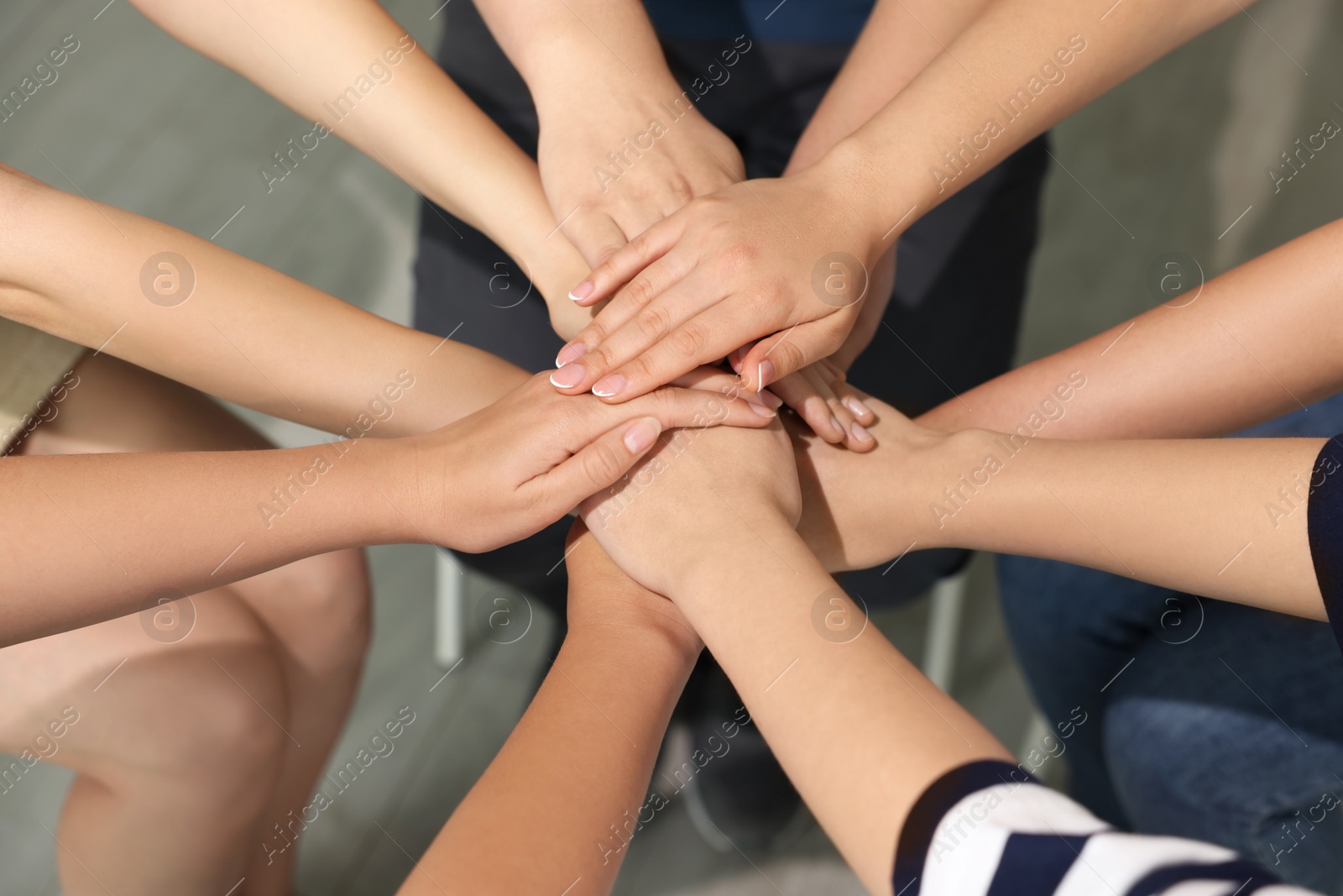 Photo of Group of people holding hands together indoors, closeup. Unity concept