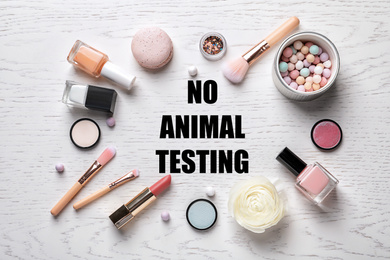 Image of Cosmetic products and text NO ANIMAL TESTING on white wooden background, flat lay