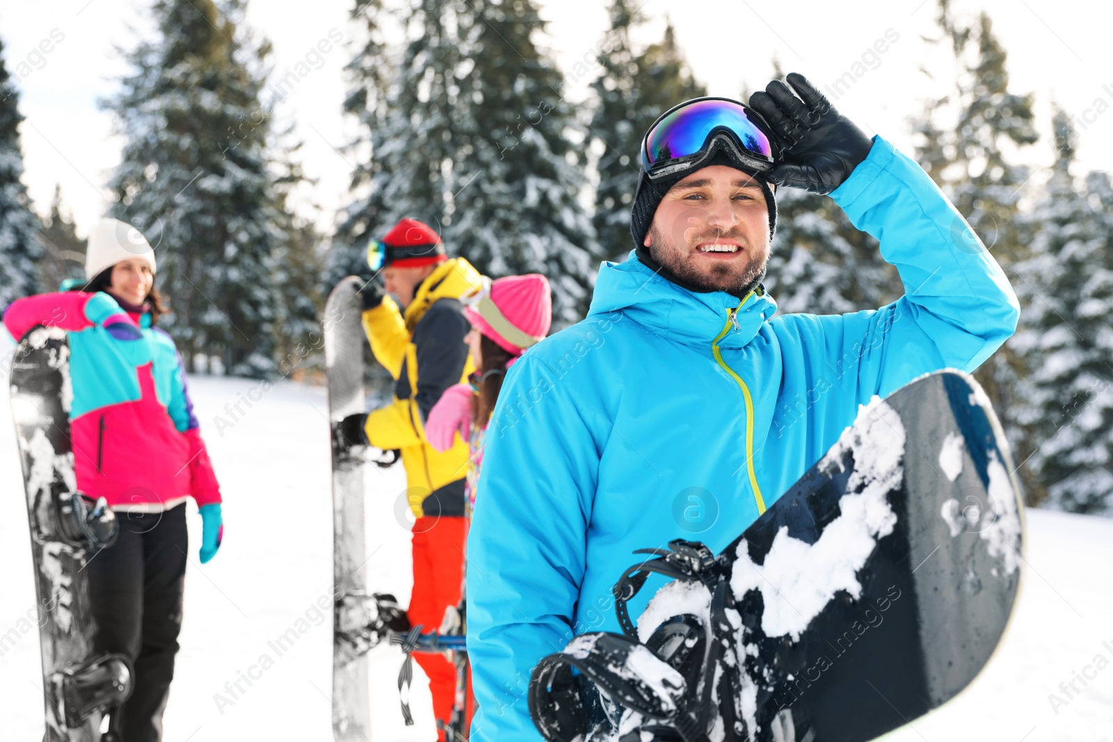 Photo of Young snowboarder with friends in snowy mountains. Winter vacation