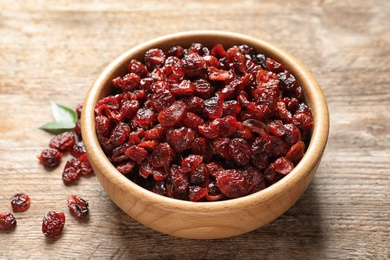 Photo of Bowl with cranberries on wooden table. Dried fruit as healthy snack