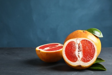 Photo of Fresh tasty grapefruits on table against color background. Space for text