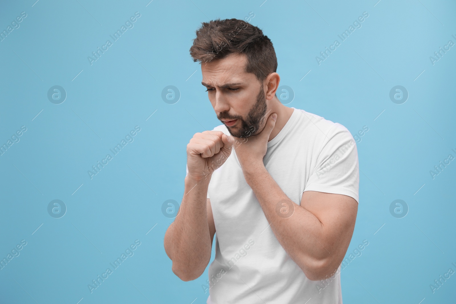 Photo of Man coughing on light blue background, space for text. Cold symptoms