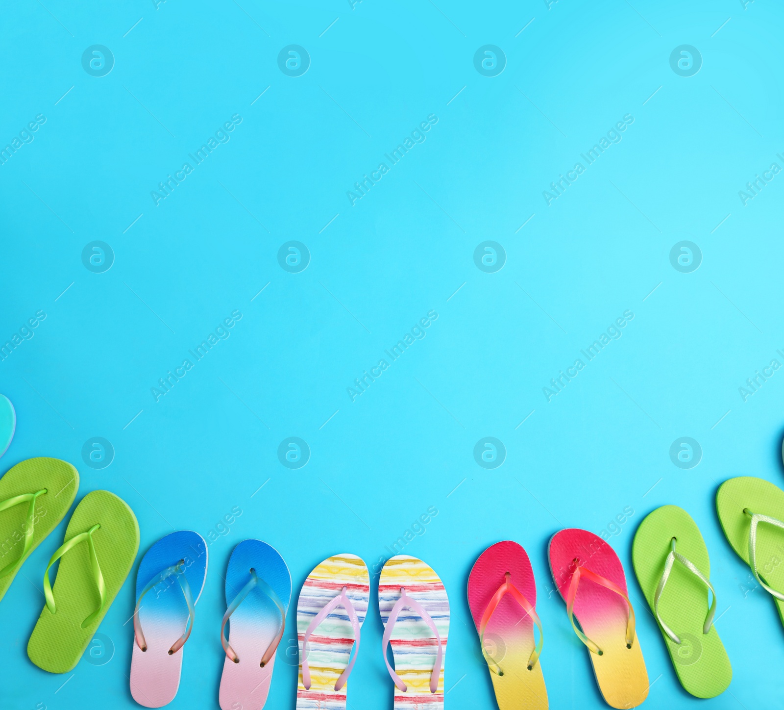 Photo of Different flip flops and space for text on blue background, flat lay. Summer beach accessories