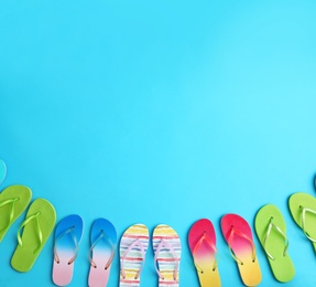 Photo of Different flip flops and space for text on blue background, flat lay. Summer beach accessories