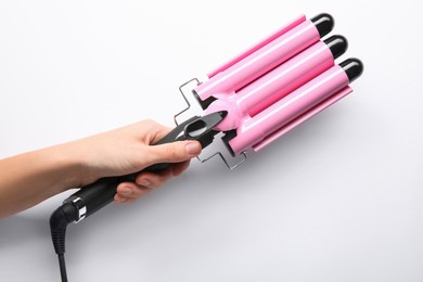 Photo of Woman holding triple curling hair iron on white background, closeup