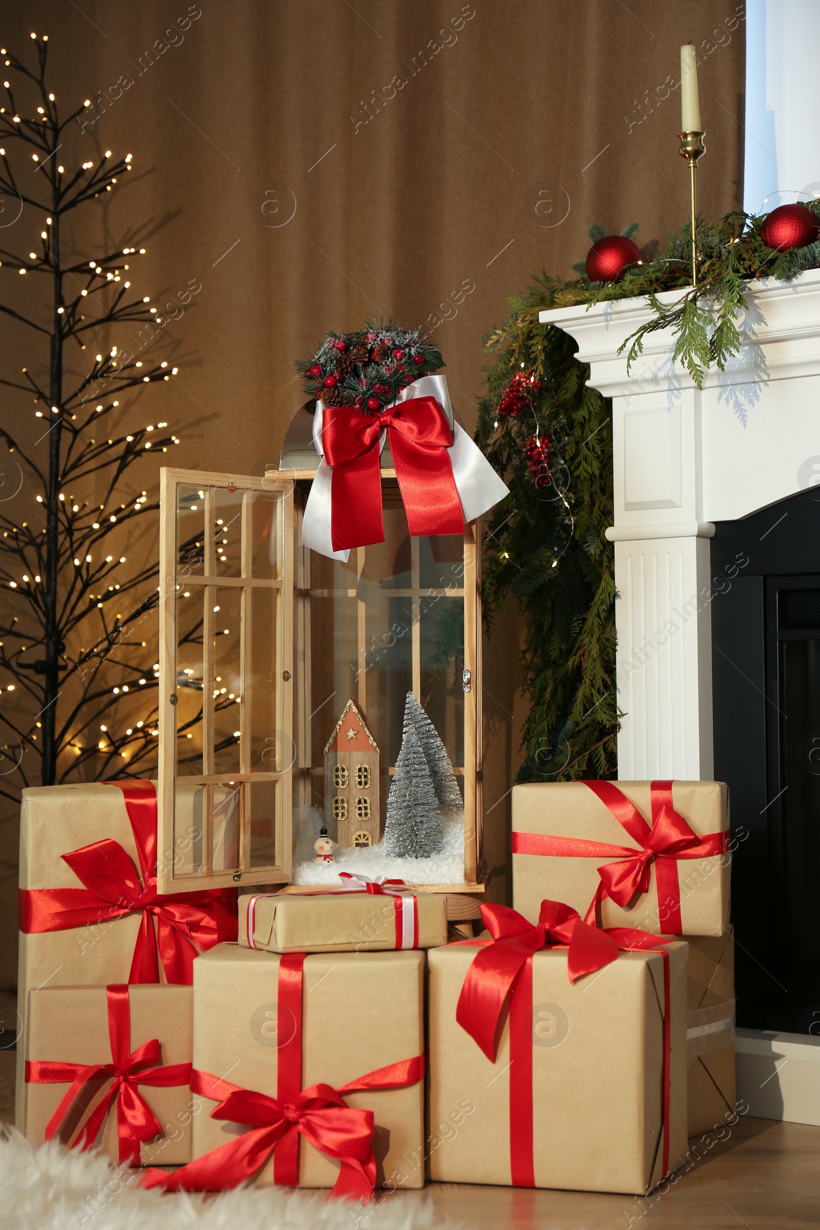 Photo of Beautiful Christmas lantern and presents near fireplace in room with festive decor