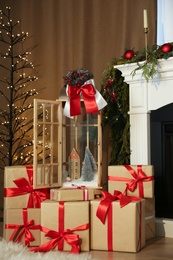 Beautiful Christmas lantern and presents near fireplace in room with festive decor