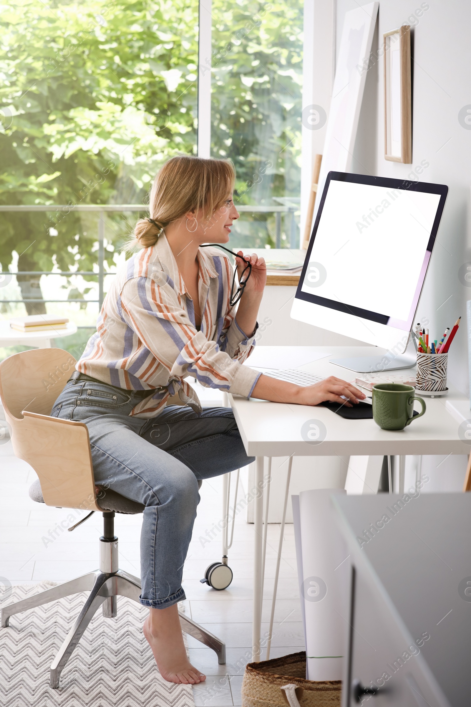 Photo of Young woman working on computer at table in room