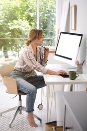 Young woman working on computer at table in room