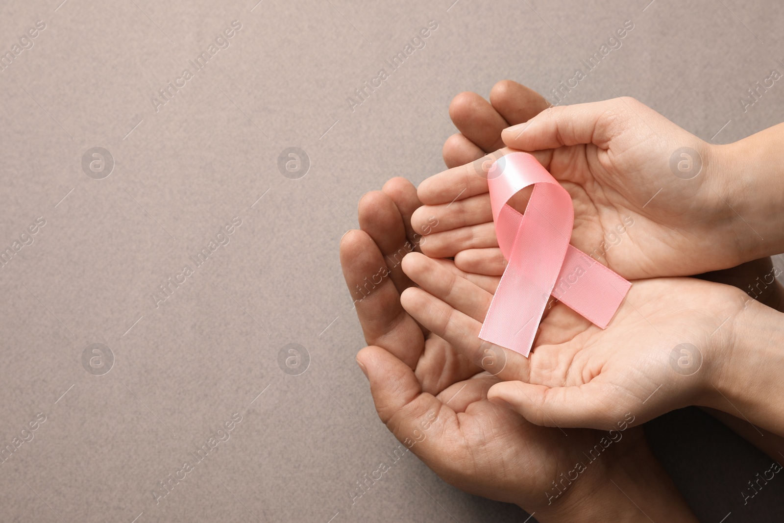 Photo of Couple holding pink ribbon on grey background, top view. Breast cancer awareness concept