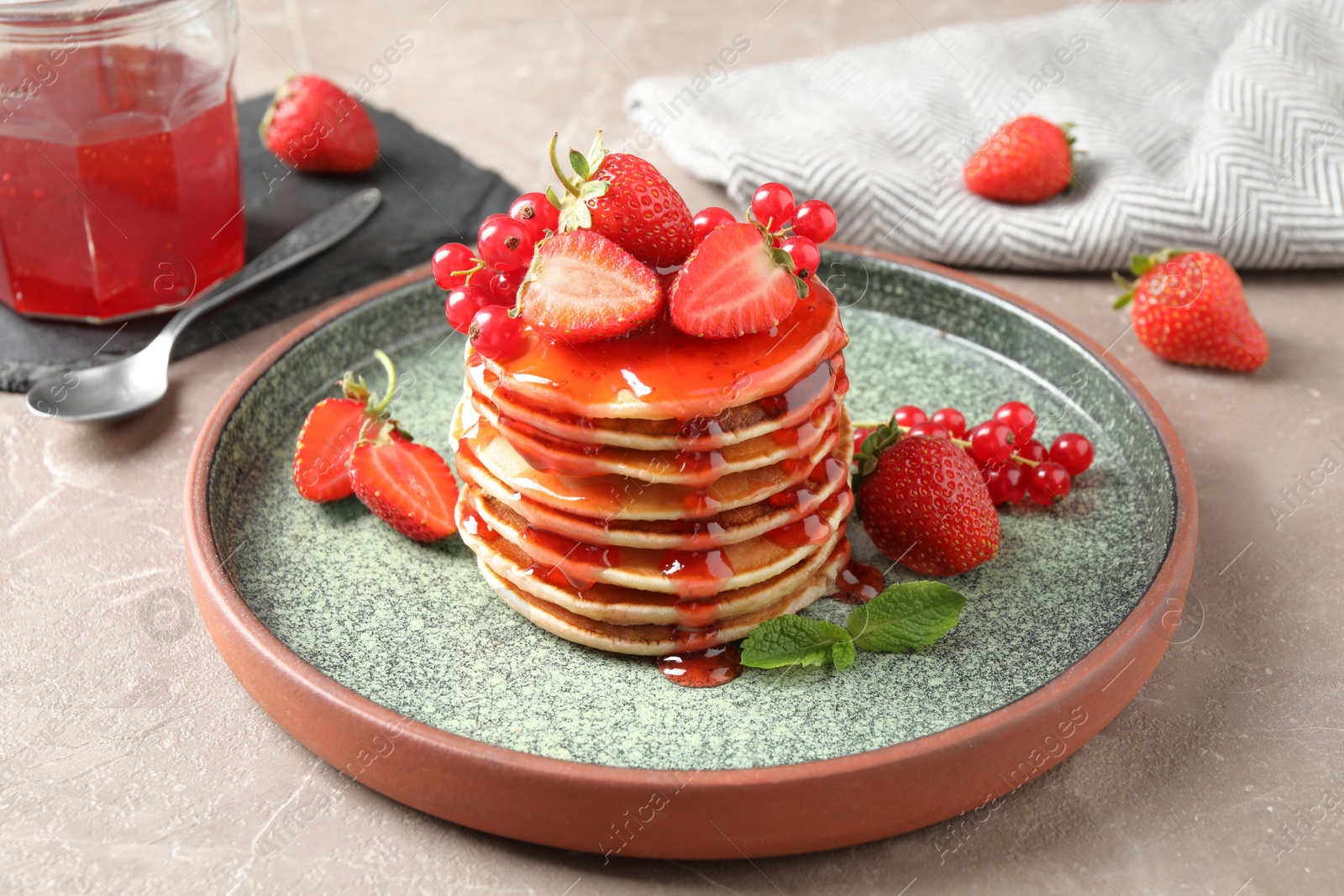 Photo of Delicious pancakes with fresh berries and syrup on beige marble table