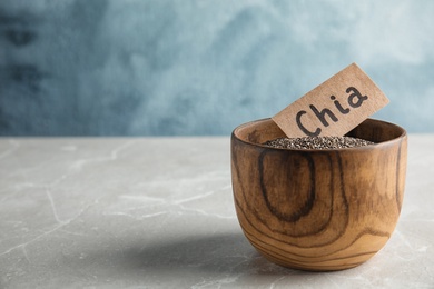 Photo of Bowl with chia seeds on table against color background, space for text