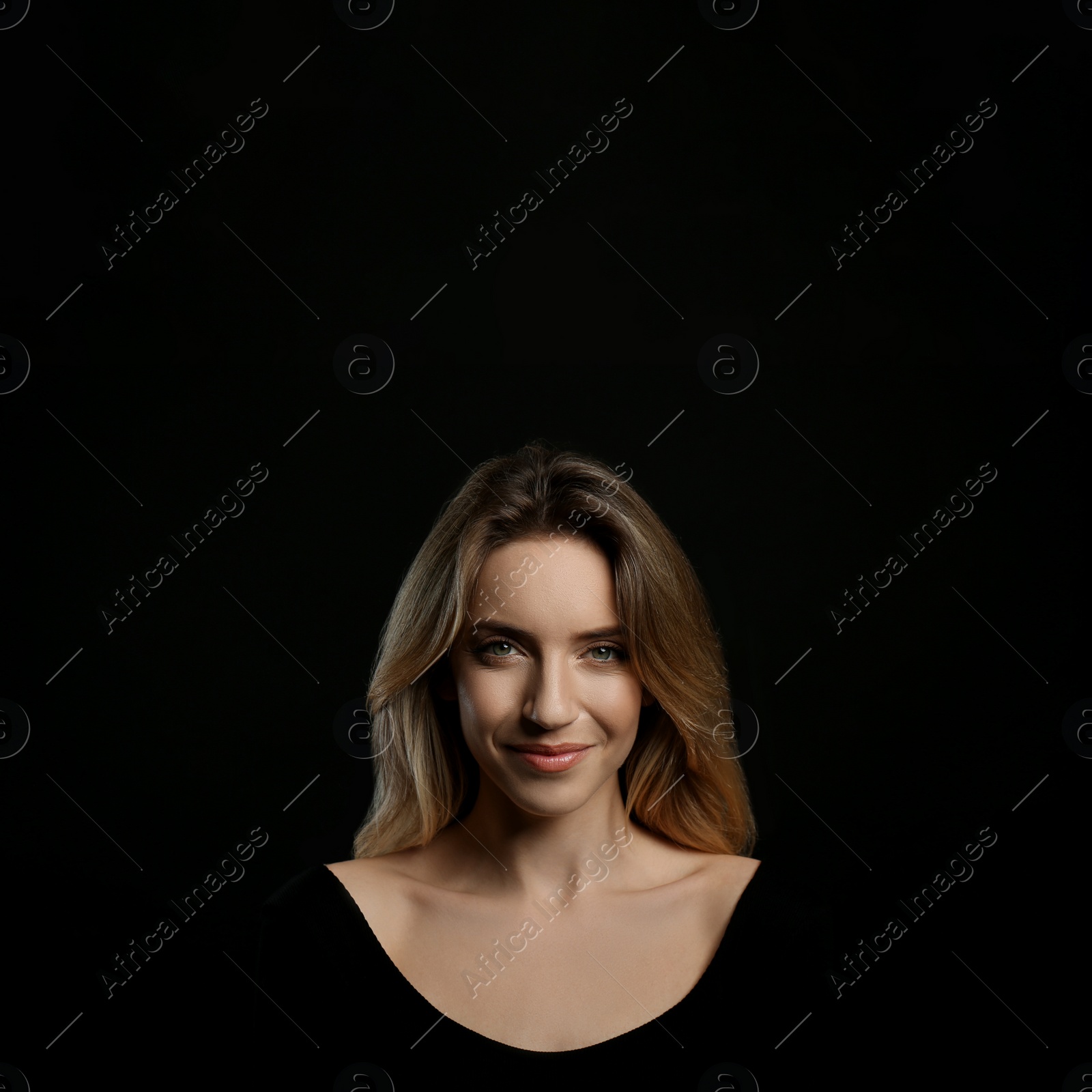 Photo of Portrait of happy young woman with beautiful blonde hair on black background