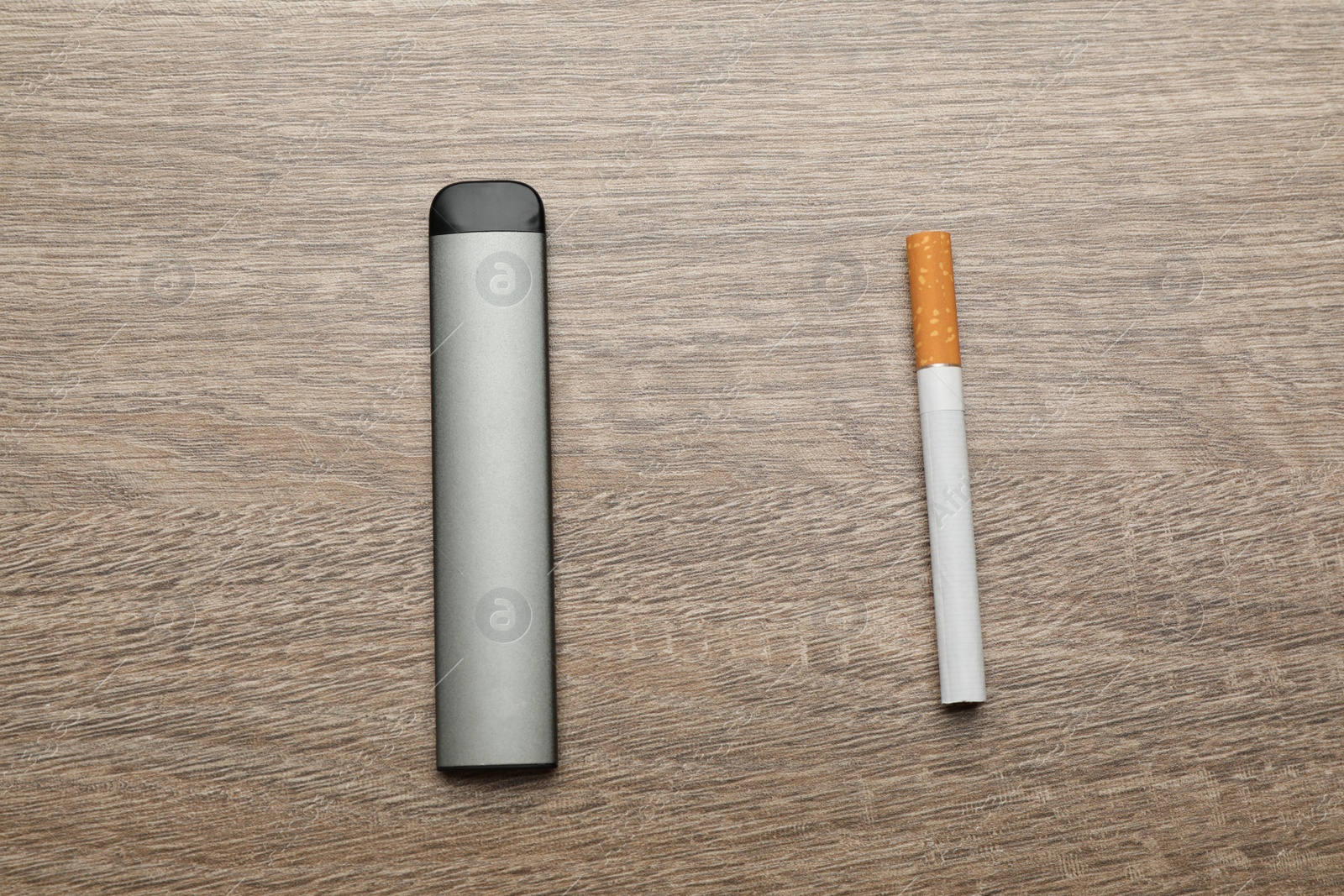 Photo of Cigarette and vaping device on wooden background, flat lay. Smoking alternative