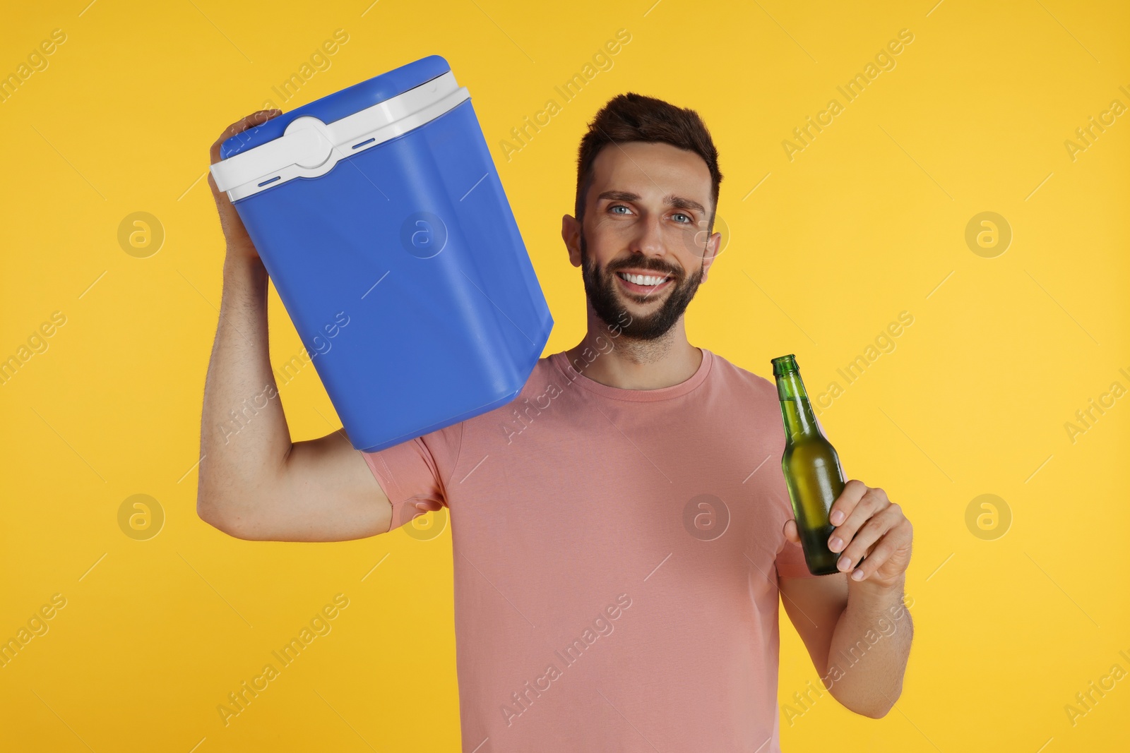 Photo of Happy man with cool box and bottle of beer on yellow background