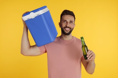 Photo of Happy man with cool box and bottle of beer on yellow background