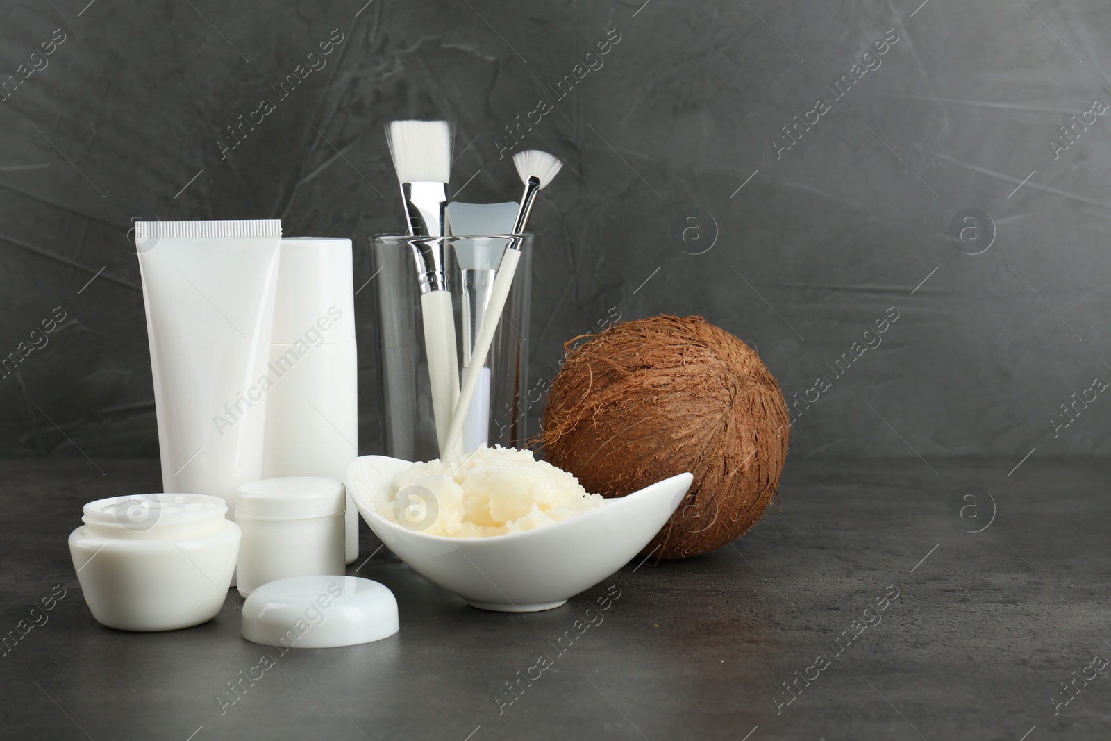 Photo of Homemade cosmetic products, tools and coconut on black table. Space for text