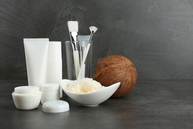 Homemade cosmetic products, tools and coconut on black table. Space for text