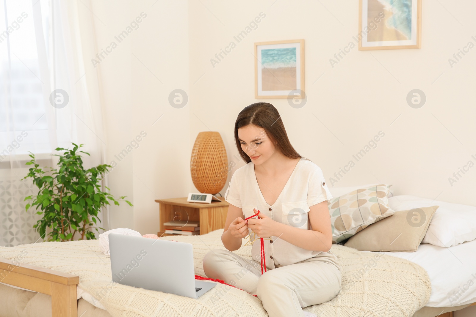 Photo of Young woman learning to knit with online course at home, space for text. Handicraft hobby