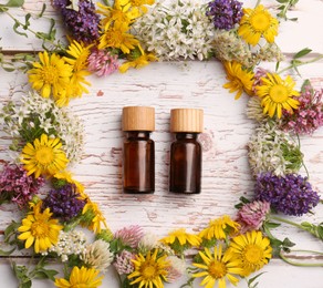 Photo of Flat lay composition with bottles of essential oils surrounded by beautiful flowers on white wooden table