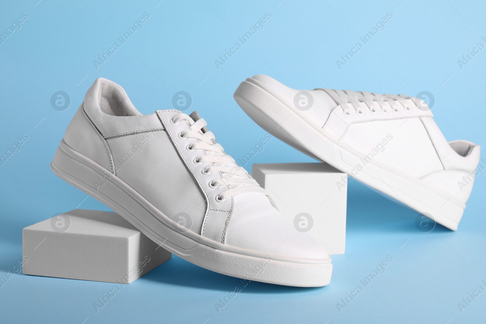 Photo of Pair of stylish white sneakers on light blue background