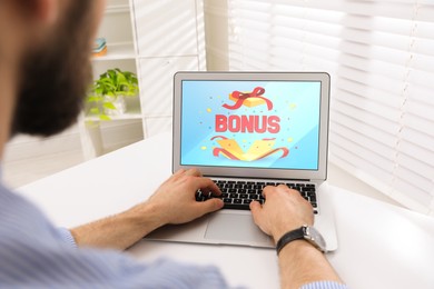 Bonus gaining. Man using laptop at white table indoors, closeup. Illustration of open gift box, word and confetti on device screen