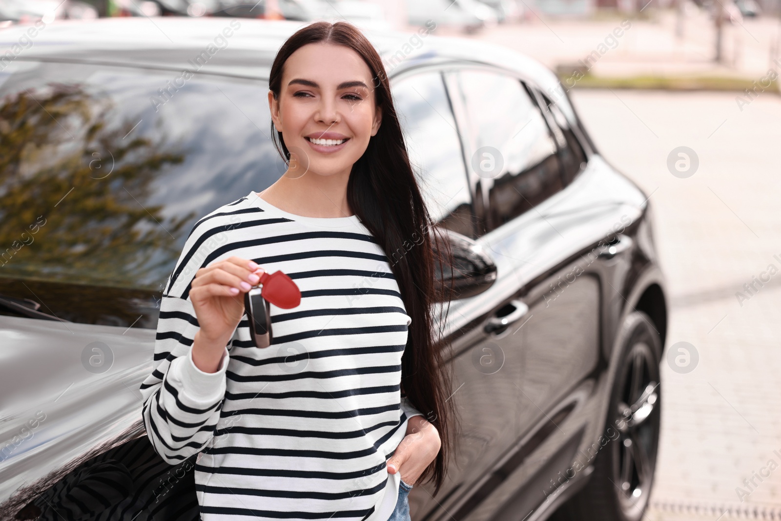 Photo of Woman holding car flip key near her vehicle outdoors