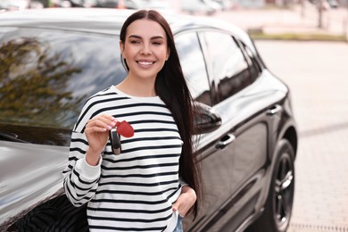 Woman holding car flip key near her vehicle outdoors