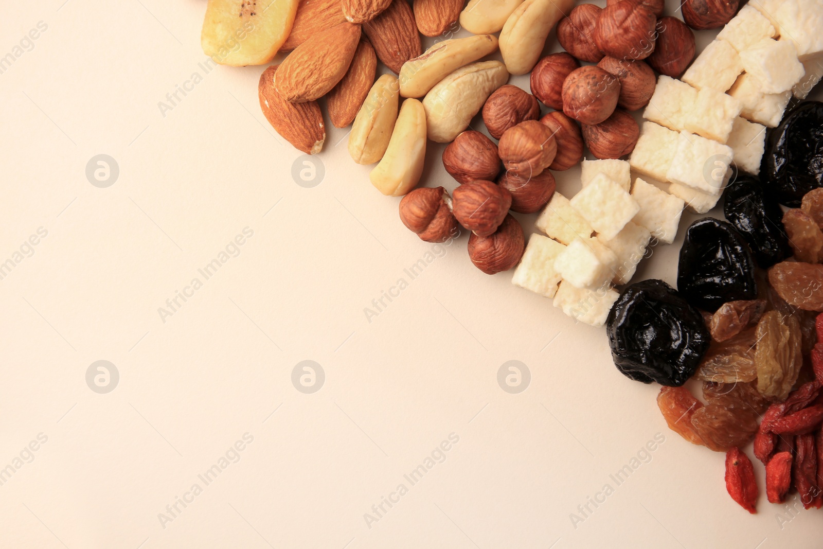 Photo of Different tasty nuts and dried fruits on beige background, flat lay. Space for text