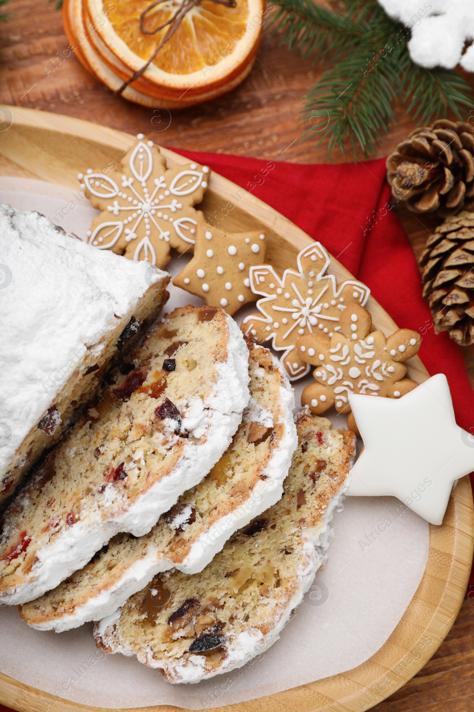 Photo of Traditional Christmas Stollen with icing sugar on wooden table, flat lay