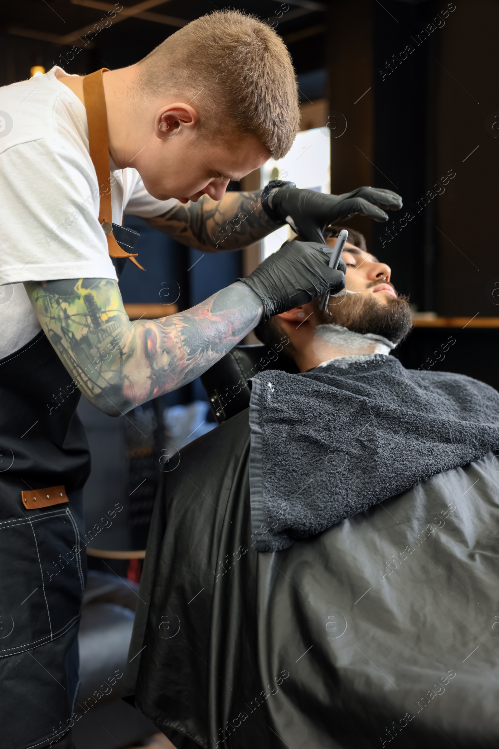 Photo of Professional hairdresser working with bearded client in barbershop