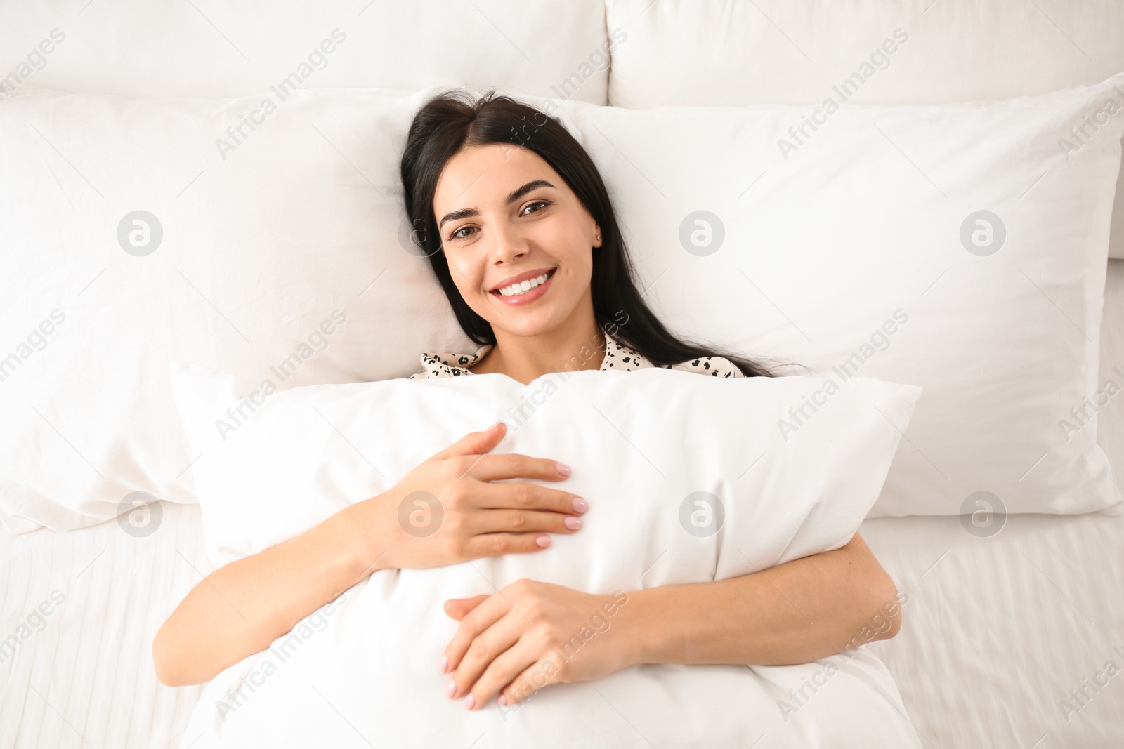 Photo of Young woman with pillow in bed, top view. Lazy morning